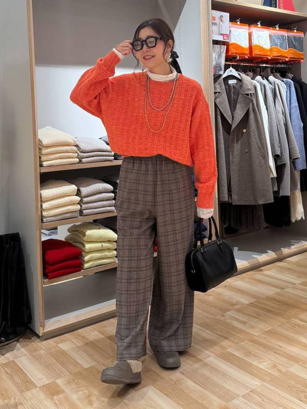 ベージュ系のダウンジャケット/コート、ホワイト系のTシャツ/カットソー、オレンジ系のニット/セーターを着用したレディースの春コーディネートの2枚目の写真