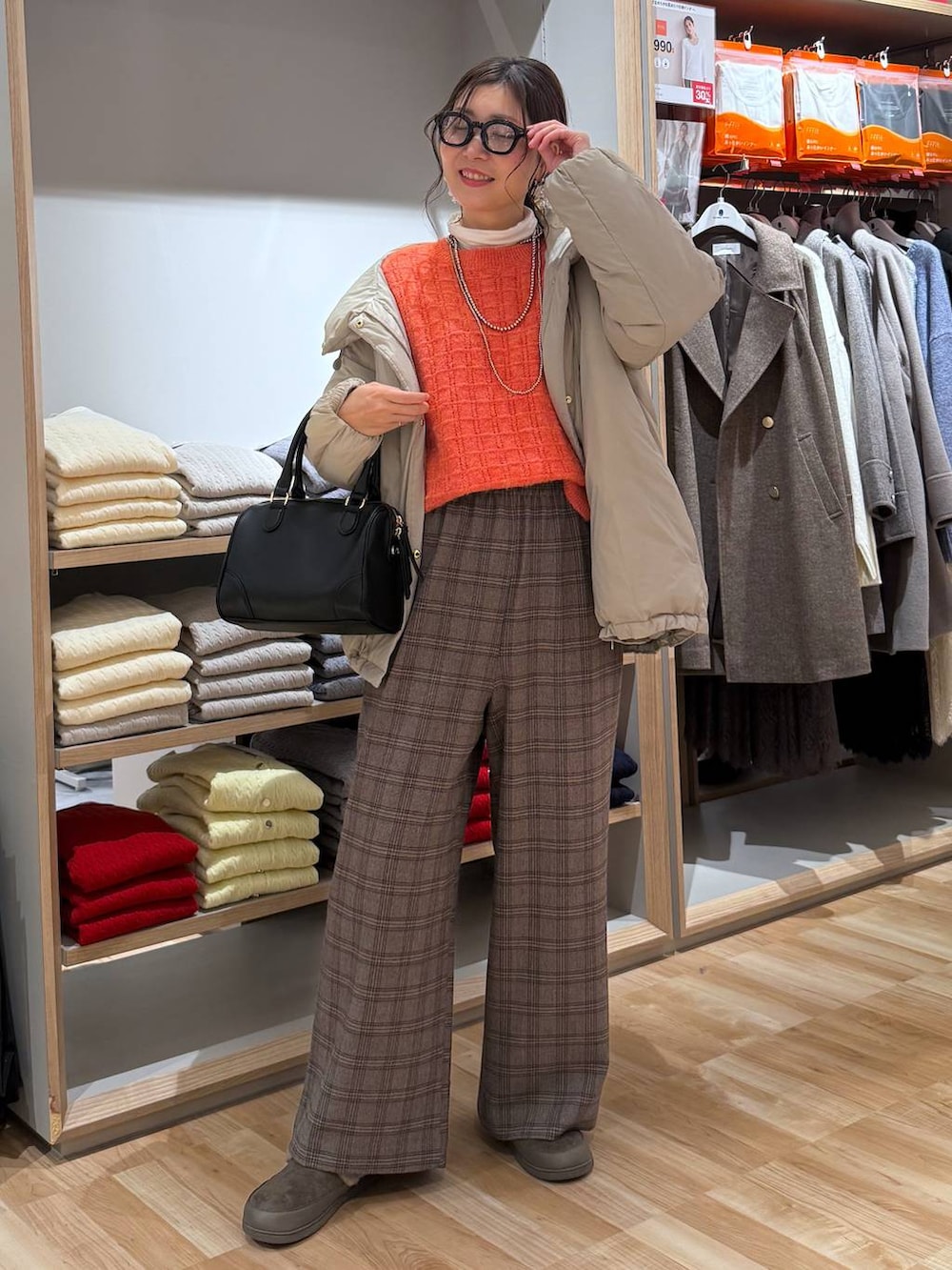 ベージュ系のダウンジャケット/コート、ホワイト系のTシャツ/カットソー、オレンジ系のニット/セーターを着用したレディースの春コーディネートの7枚目の写真