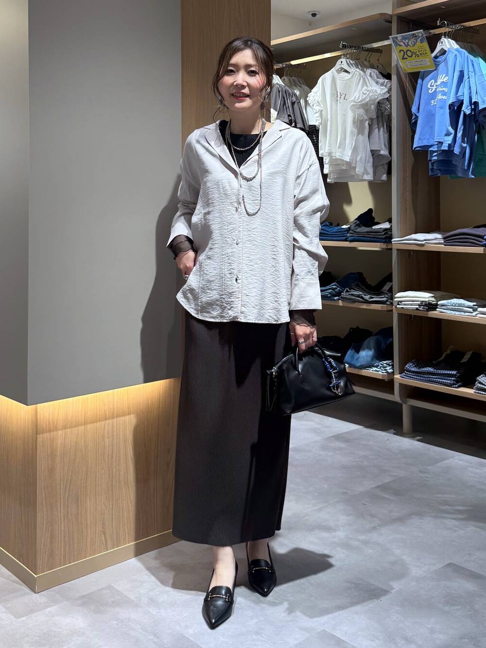 ブラック系のTシャツ/カットソー、ブラウン系のスカート、ブラック系のローファーを着用したレディースの春コーディネートの2枚目の写真