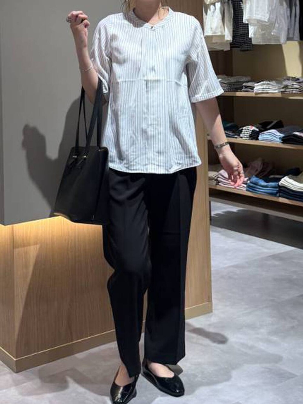 ブラック系のパンプス、ブラック系のトートバッグ、ホワイト系のシャツ/ブラウスを着用したレディースの夏コーディネートの5枚目の写真