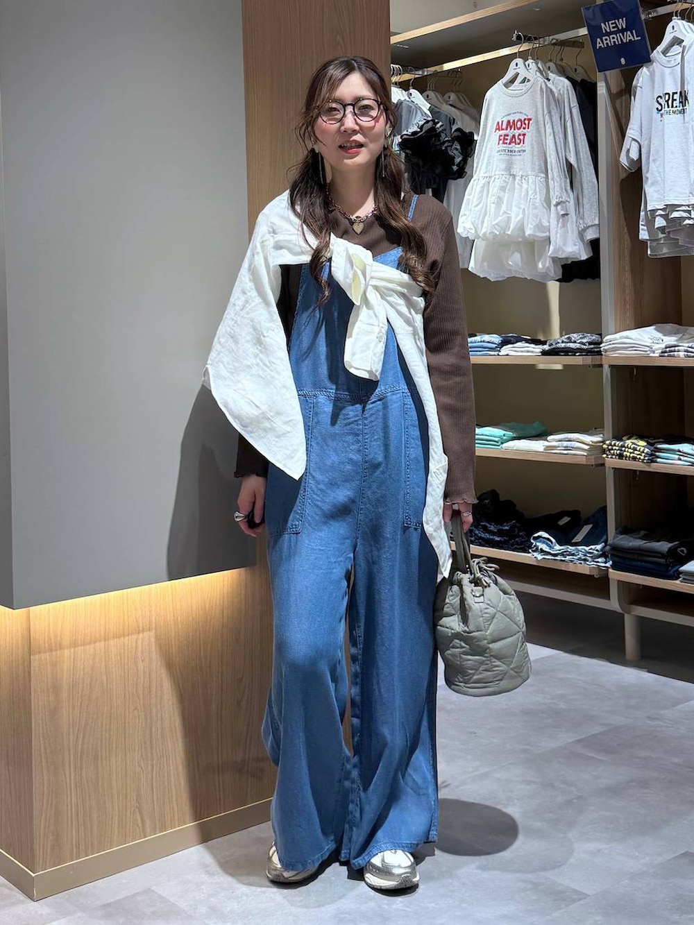 グリーン系のハンドバッグ、ホワイト系のシャツ/ブラウス、ブルー系のサロペット/オーバーオールを着用したレディースの春コーディネートの6枚目の写真