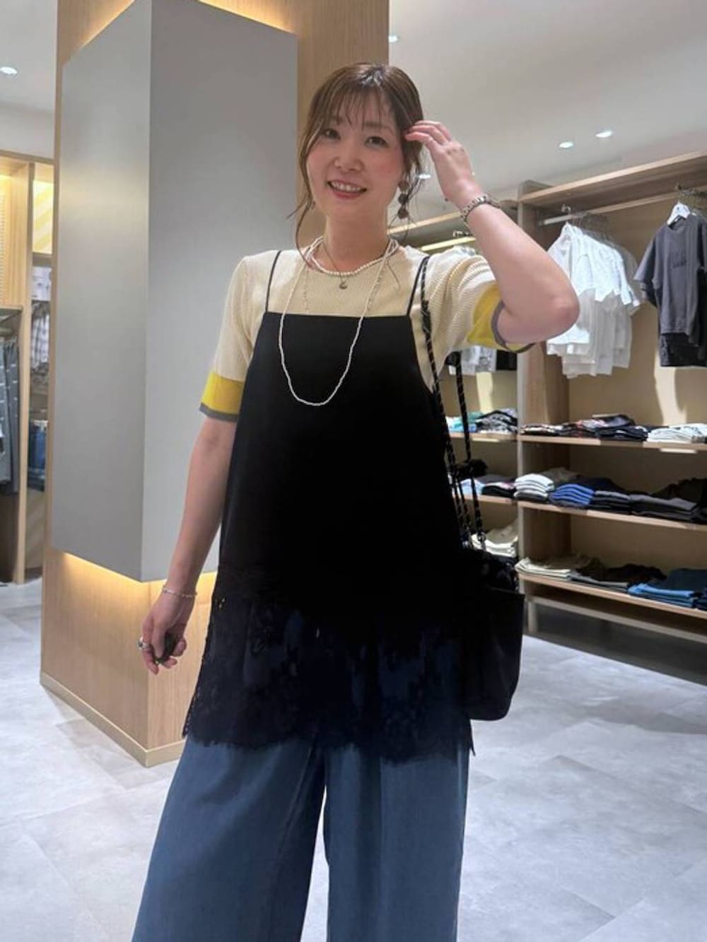 ブルー系のデニムパンツ、グレー系のボディバッグ/ウエストポーチ、イエロー系のニット/セーターを着用したレディースの夏コーディネートの3枚目の写真