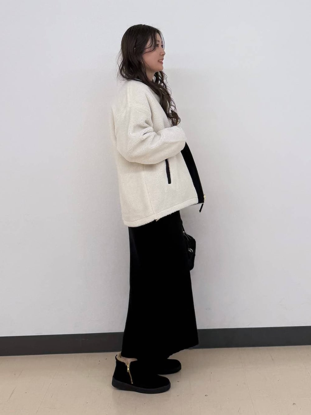 ホワイト系のブルゾン、ブラック系のボストンバッグ、ブラック系のスカートを着用したレディースの冬コーディネートの7枚目の写真