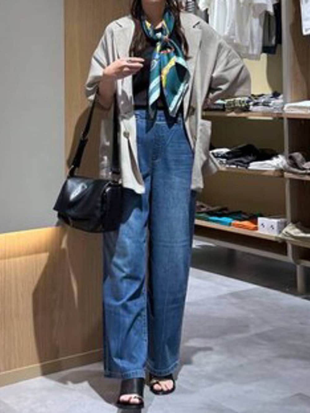 ブルー系のデニムパンツ、ベージュ系のテーラードジャケット、ブラック系のサンダルを着用したレディースの夏コーディネートの5枚目の写真