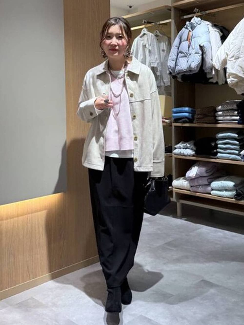 ブラック系のショルダーバッグ、ホワイト系のTシャツ/カットソー、ブラック系のブーツを着用したレディースの冬コーディネートの2枚目の写真