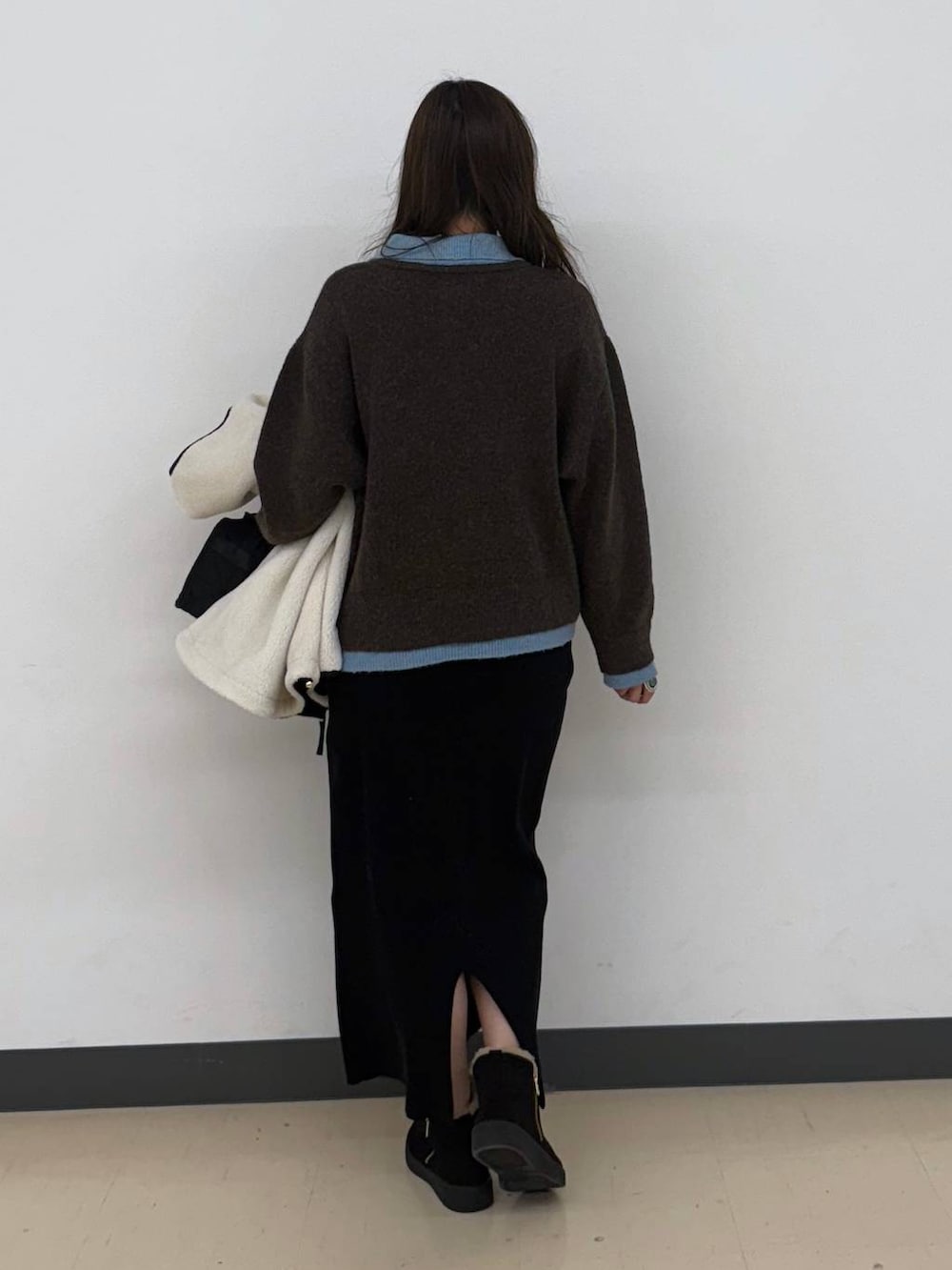 ホワイト系のブルゾン、ブラック系のボストンバッグ、ブラック系のスカートを着用したレディースの冬コーディネートの4枚目の写真