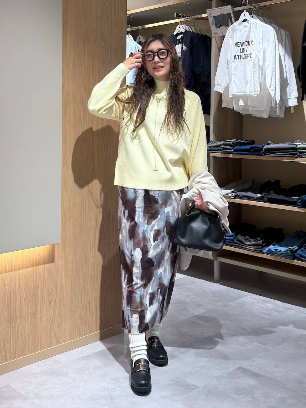 ブラック系のショルダーバッグ、ブラック系のローファー、イエロー系のニット/セーターを着用したレディースの冬コーディネートの6枚目の写真