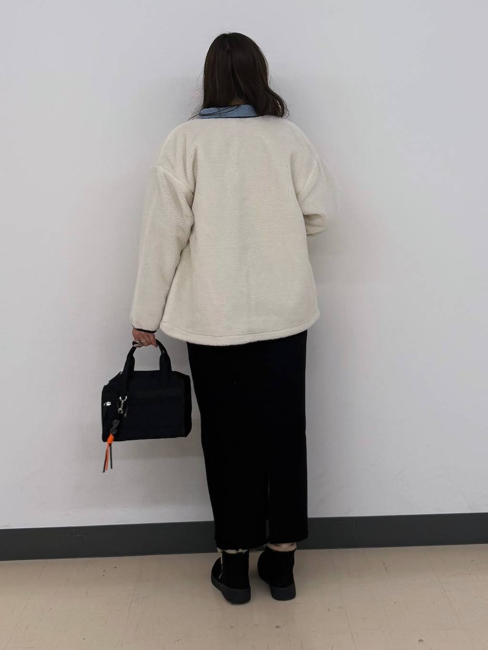 ホワイト系のブルゾン、ブラック系のボストンバッグ、ブラック系のスカートを着用したレディースの冬コーディネートの8枚目の写真