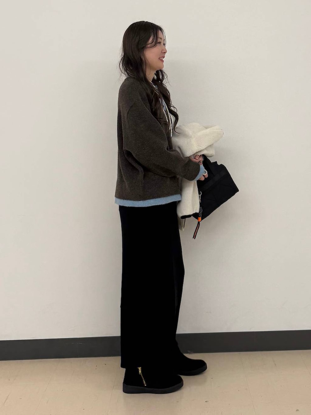 ホワイト系のブルゾン、ブラック系のボストンバッグ、ブラック系のスカートを着用したレディースの冬コーディネートの3枚目の写真