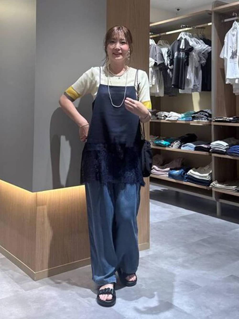 ブルー系のデニムパンツ、グレー系のボディバッグ/ウエストポーチ、イエロー系のニット/セーターを着用したレディースの夏コーディネートの2枚目の写真