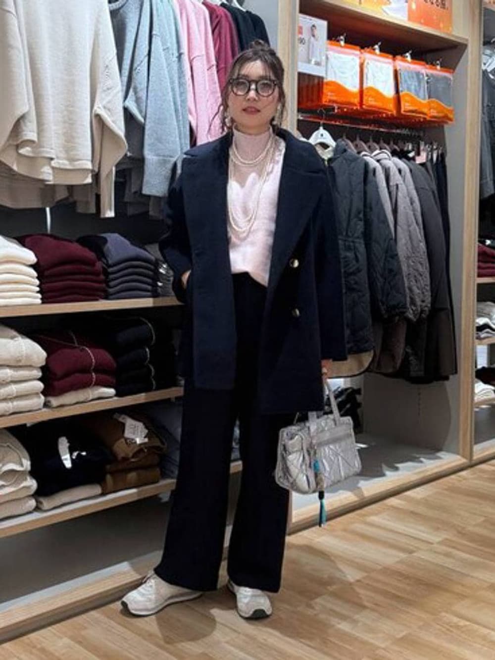 ブルー系のチェスターコート、シルバー系のボストンバッグ、ピンク系のニット/セーターを着用したレディースの冬コーディネートの2枚目の写真