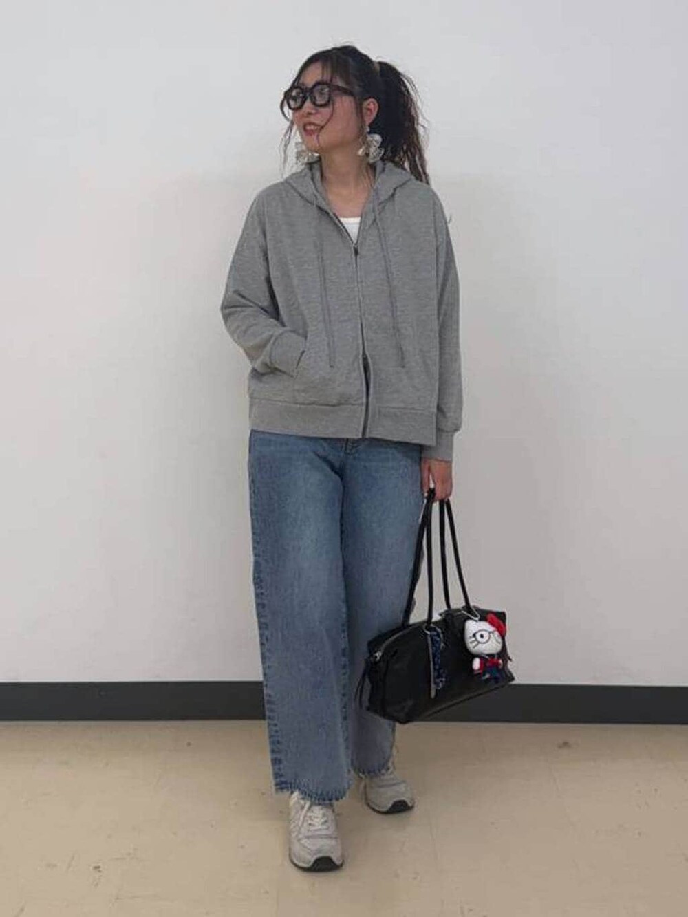 ブルー系のデニムパンツ、グレー系のパーカー、ブラック系のボストンバッグを着用したレディースの冬コーディネートの2枚目の写真