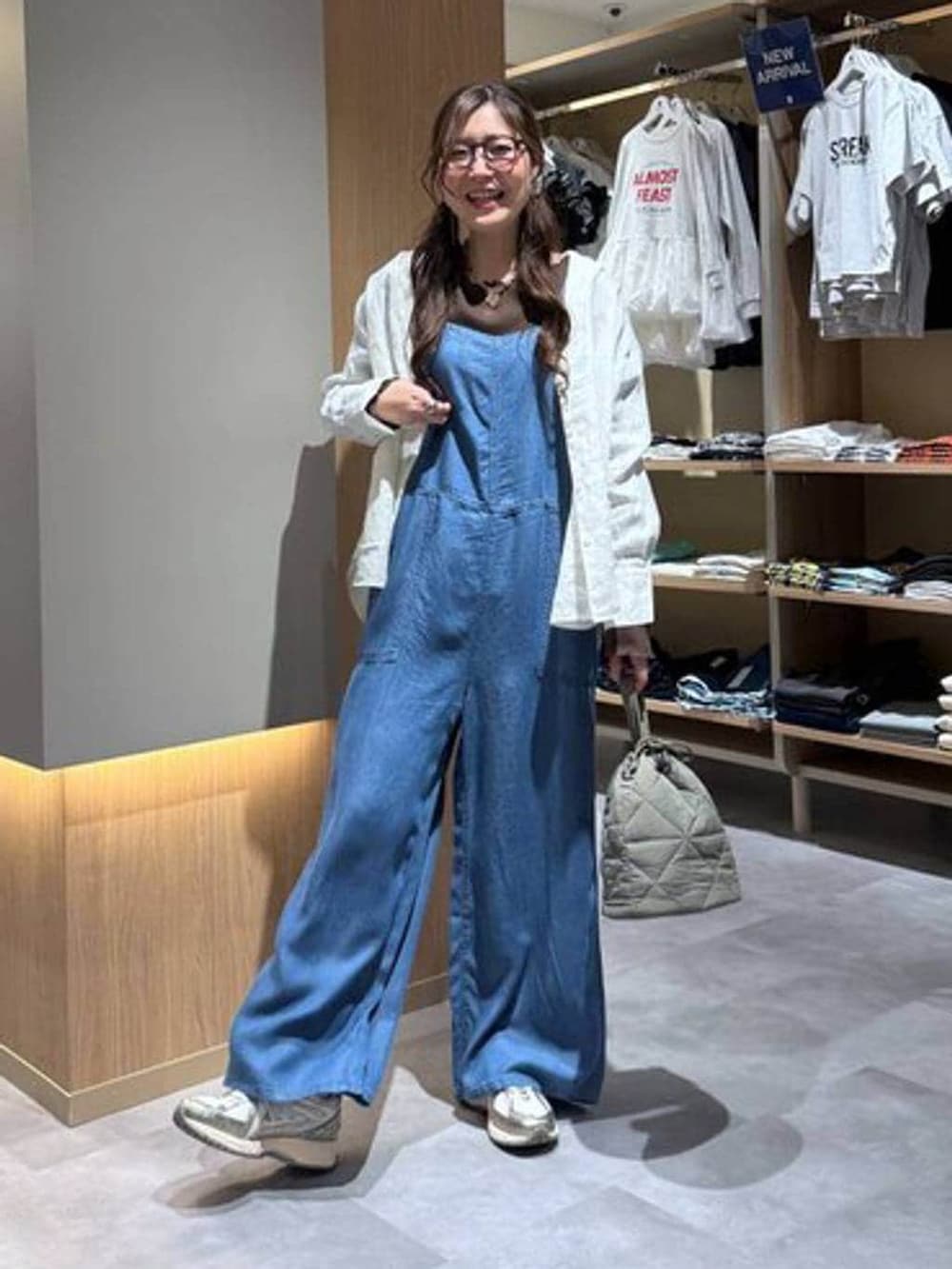 グリーン系のハンドバッグ、ホワイト系のシャツ/ブラウス、ブルー系のサロペット/オーバーオールを着用したレディースの春コーディネートの2枚目の写真