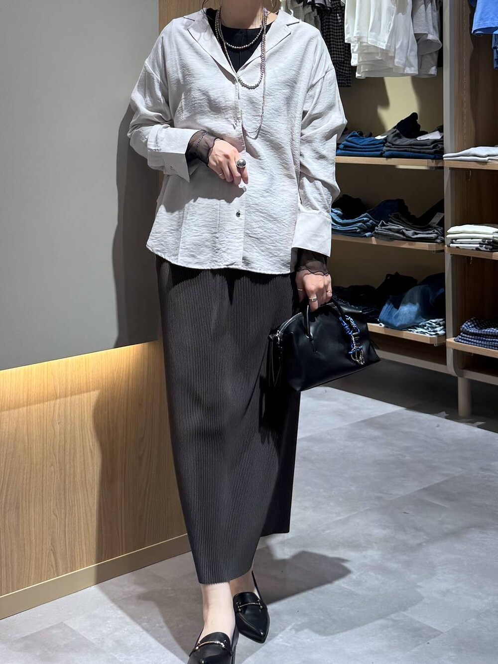 ブラック系のTシャツ/カットソー、ブラウン系のスカート、ブラック系のローファーを着用したレディースの春コーディネートの5枚目の写真