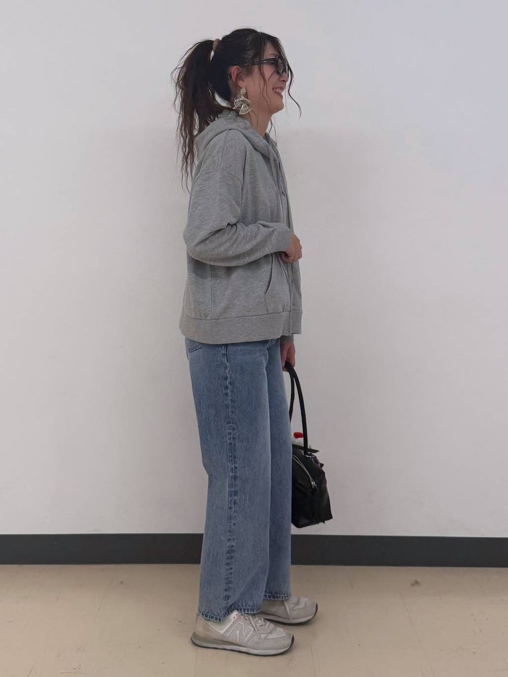 ブルー系のデニムパンツ、グレー系のパーカー、ブラック系のボストンバッグを着用したレディースの冬コーディネートの4枚目の写真