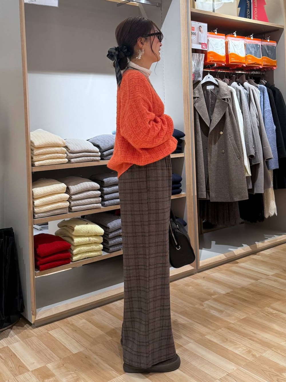 ベージュ系のダウンジャケット/コート、ホワイト系のTシャツ/カットソー、オレンジ系のニット/セーターを着用したレディースの春コーディネートの4枚目の写真