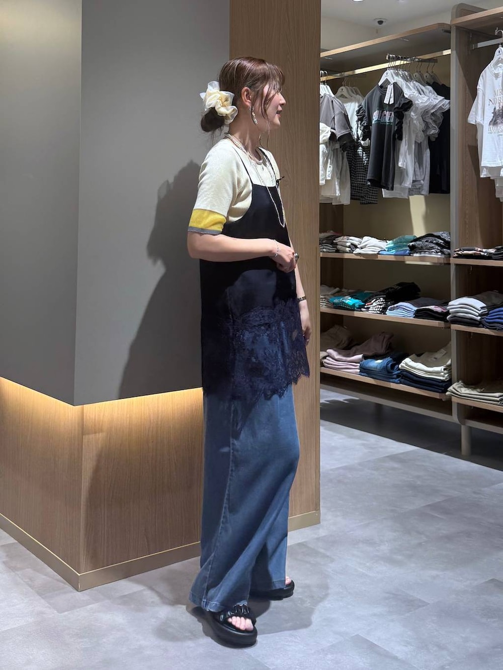 ブルー系のデニムパンツ、グレー系のボディバッグ/ウエストポーチ、イエロー系のニット/セーターを着用したレディースの夏コーディネートの4枚目の写真
