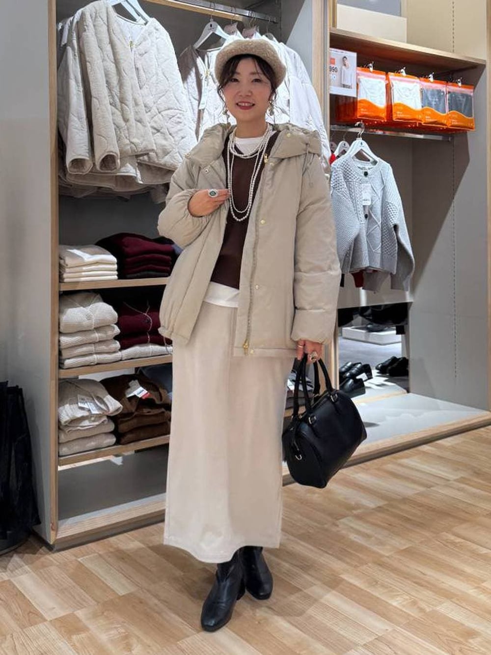 ベージュ系のダウンジャケット/コート、ブラウン系のスウェット、グレー系のスカートを着用したレディースの冬コーディネートの2枚目の写真