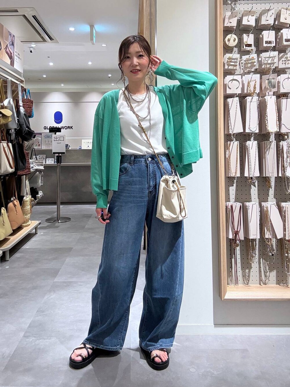 ブルー系のデニムパンツ、グリーン系のカーディガン/ボレロ、ベージュ系のボディバッグ/ウエストポーチを着用したレディースの夏コーディネートの7枚目の写真