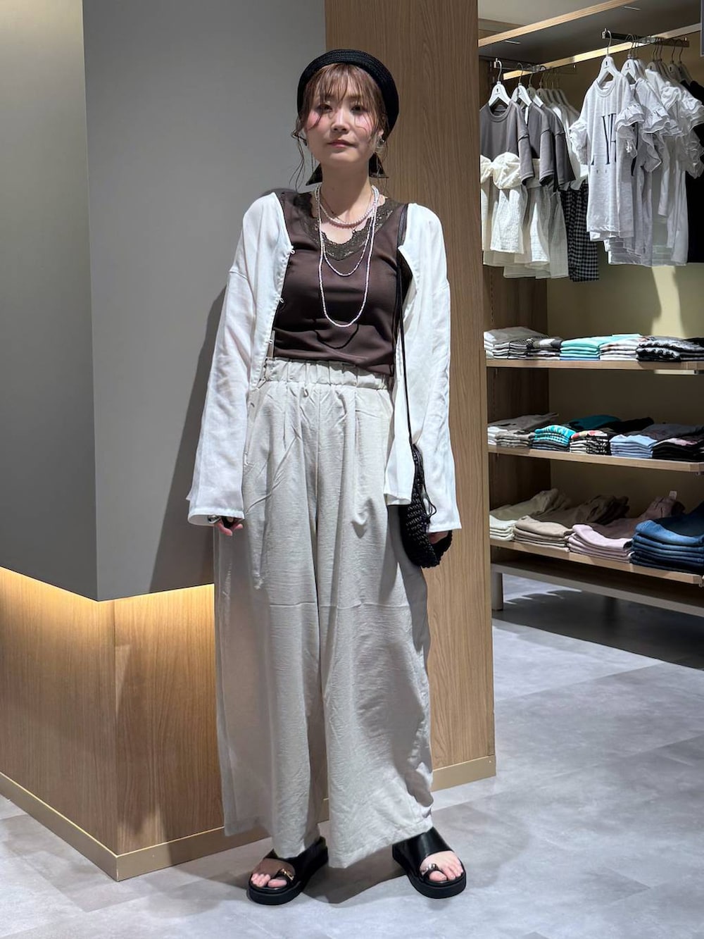 ベージュ系のその他パンツ、ホワイト系のカーディガン/ボレロ、シルバー系のネックレスを着用したレディースの夏コーディネートの2枚目の写真