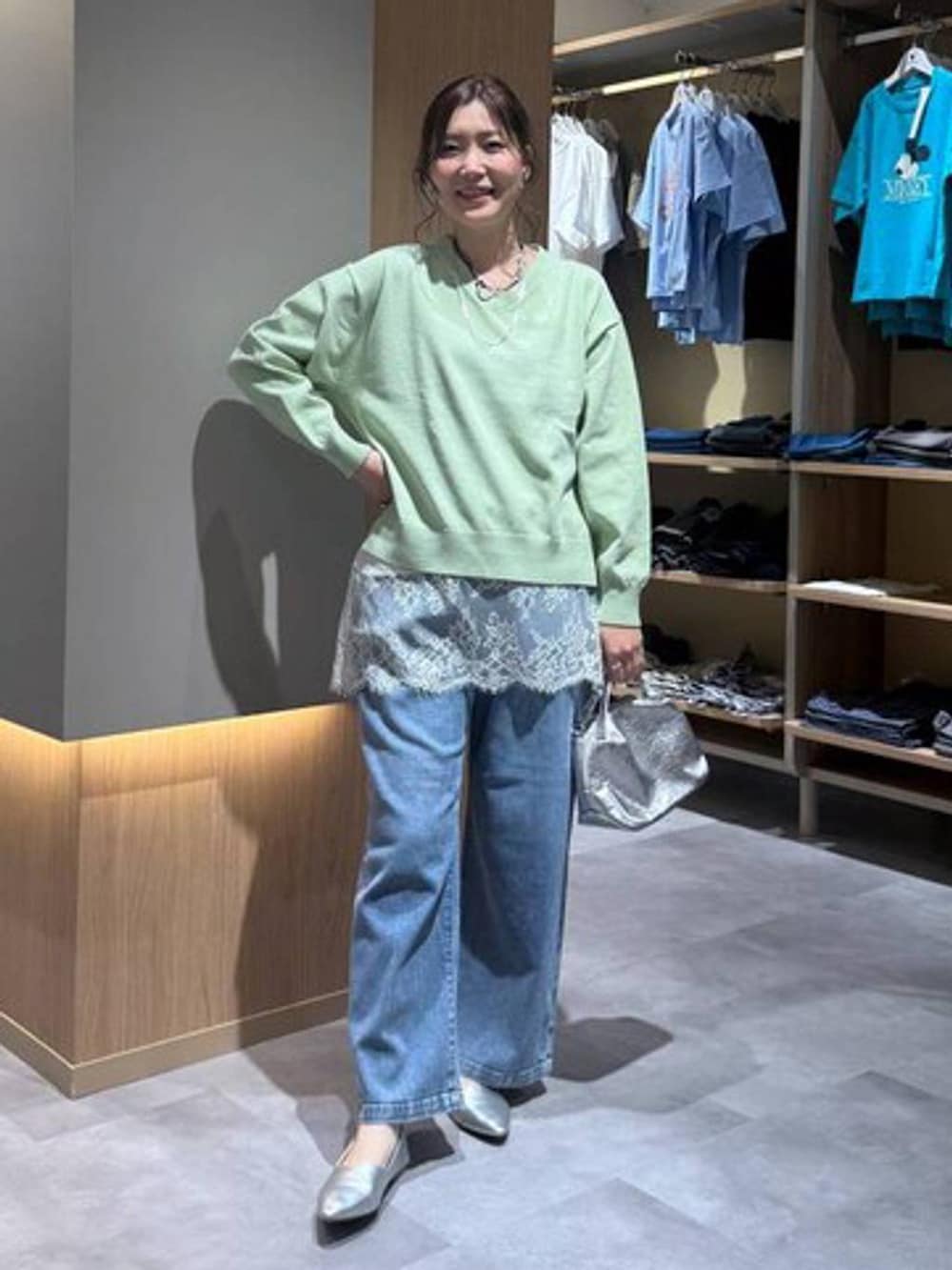 シルバー系のショルダーバッグ、シルバー系のパンプス、グリーン系のニット/セーターを着用したレディースの春コーディネートの2枚目の写真