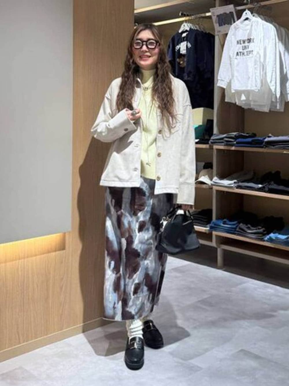 ブラック系のショルダーバッグ、ブラック系のローファー、イエロー系のニット/セーターを着用したレディースの冬コーディネートの2枚目の写真