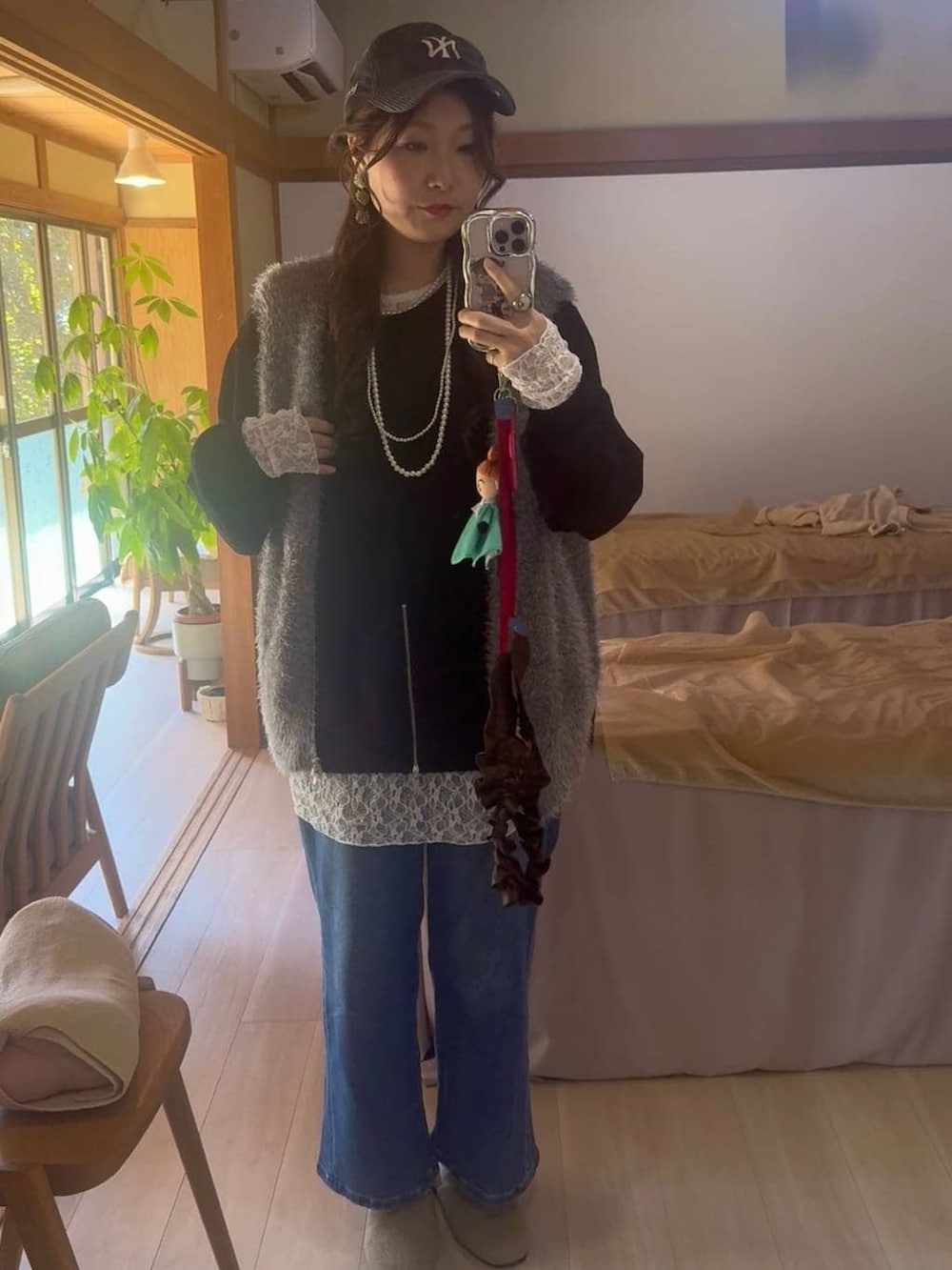 グレー系のベスト、ブルー系のデニムパンツ、ブラック系のTシャツ/カットソーを着用したレディースの春コーディネートの2枚目の写真