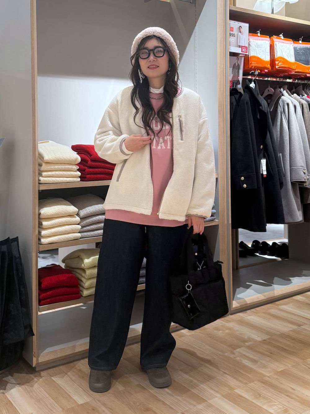 ブラック系のトートバッグ、ホワイト系のブルゾン、ブルー系のデニムパンツを着用したレディースの冬コーディネートの2枚目の写真