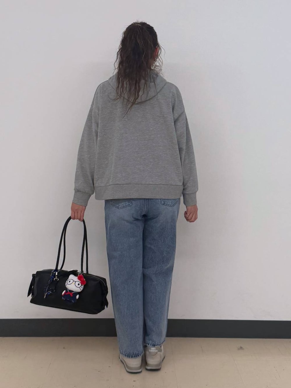 ブルー系のデニムパンツ、グレー系のパーカー、ブラック系のボストンバッグを着用したレディースの冬コーディネートの5枚目の写真