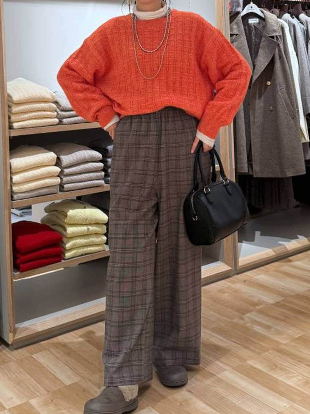 ベージュ系のダウンジャケット/コート、ホワイト系のTシャツ/カットソー、オレンジ系のニット/セーターを着用したレディースの春コーディネートの6枚目の写真