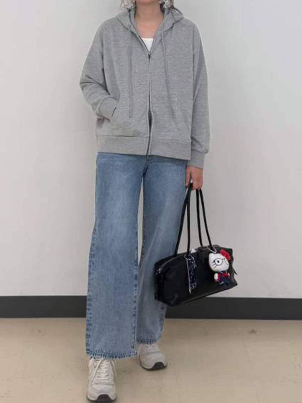 ブルー系のデニムパンツ、グレー系のパーカー、ブラック系のボストンバッグを着用したレディースの冬コーディネートの6枚目の写真