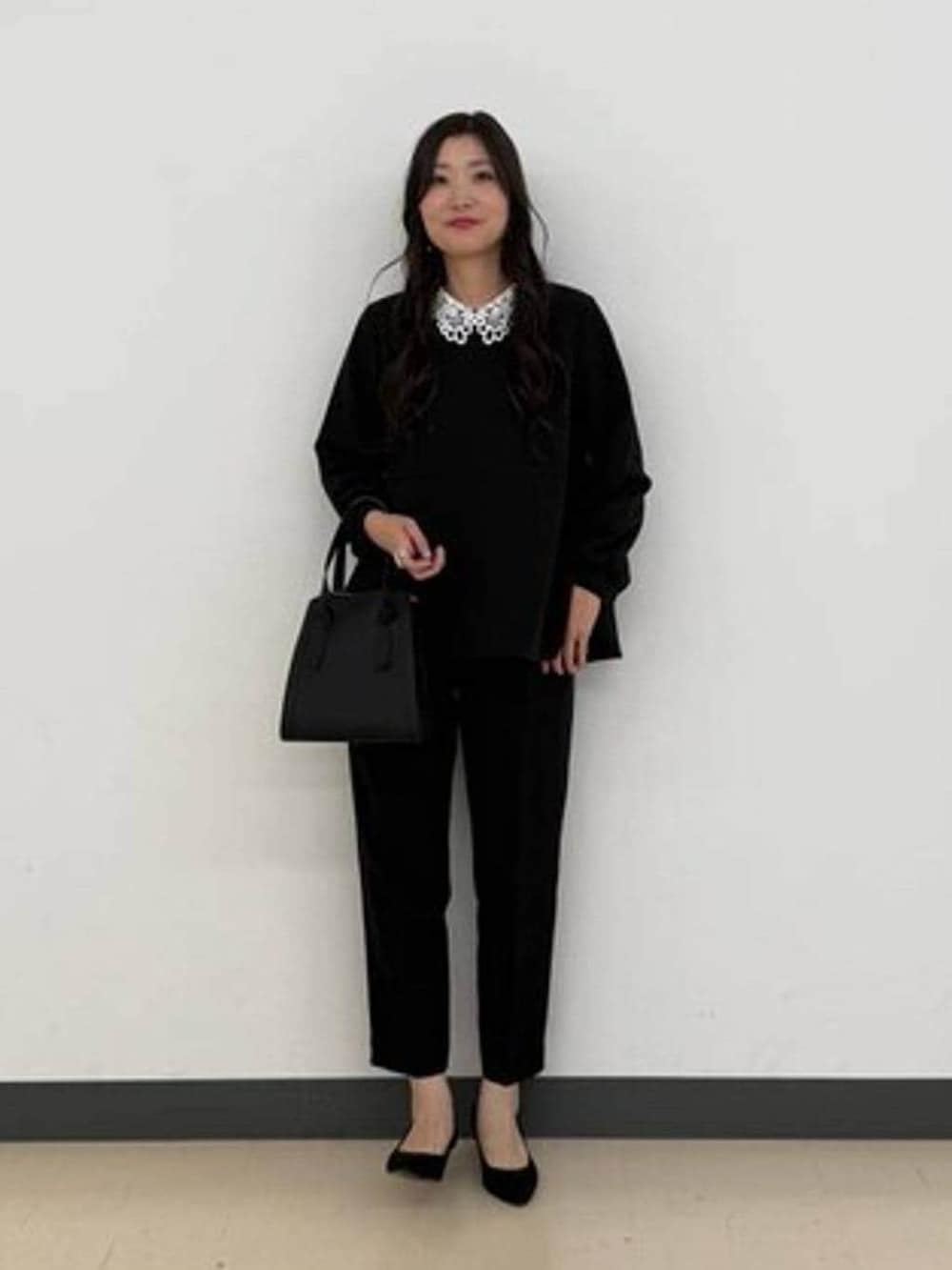 ブラック系のショルダーバッグ、ブラック系のセットアップ、ブラック系のパンプスを着用したレディースの冬コーディネートの2枚目の写真