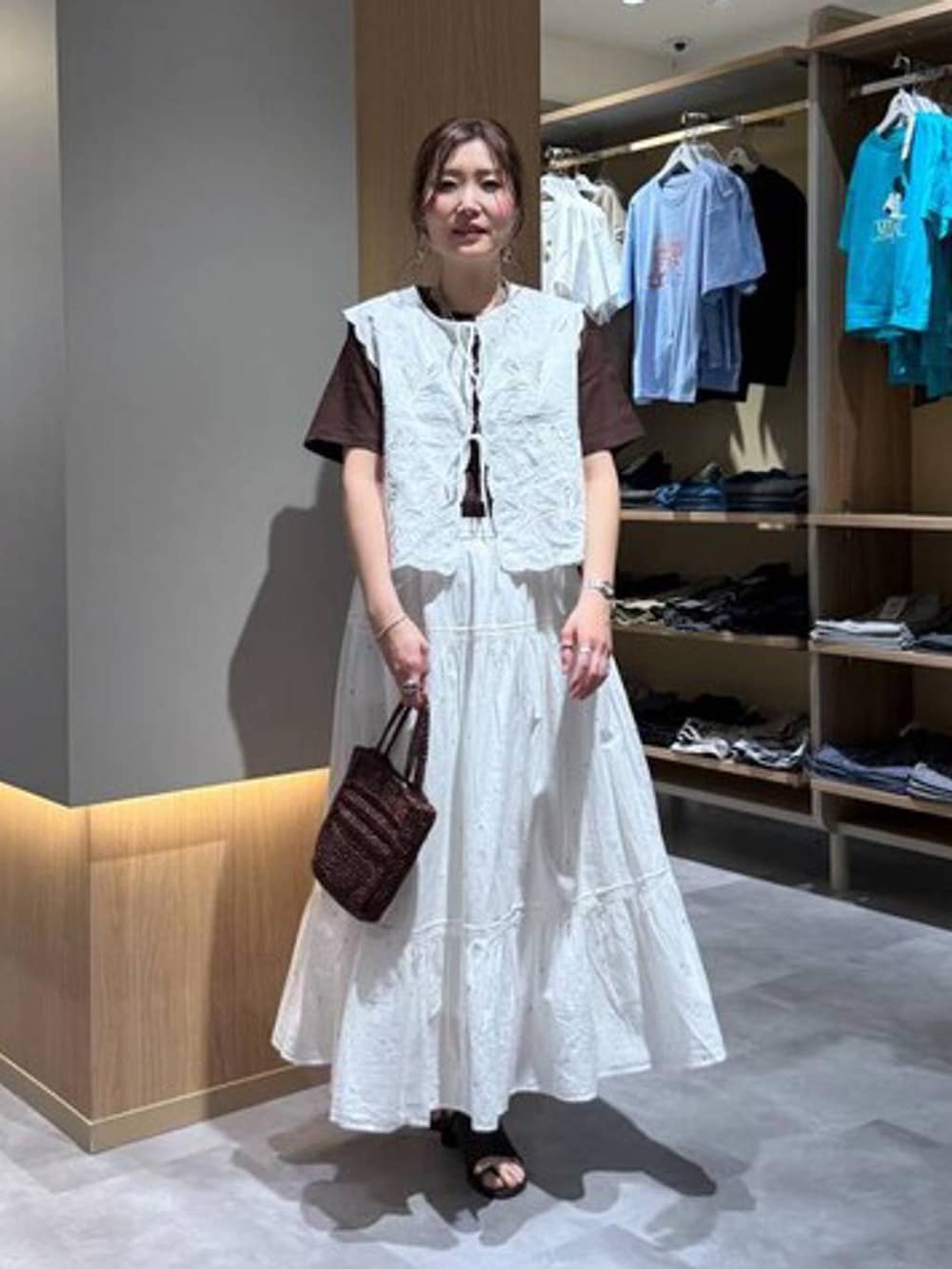 ホワイト系のベスト、ホワイト系のスカート、ブラウン系のTシャツ/カットソーを着用したレディースの夏コーディネートの2枚目の写真