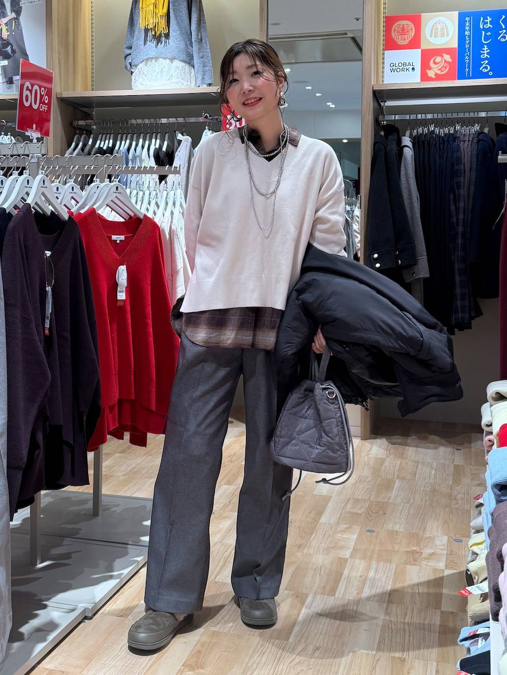 ブラック系のブルゾン、グレー系のハンドバッグ、ホワイト系のニット/セーターを着用したレディースの冬コーディネートの2枚目の写真