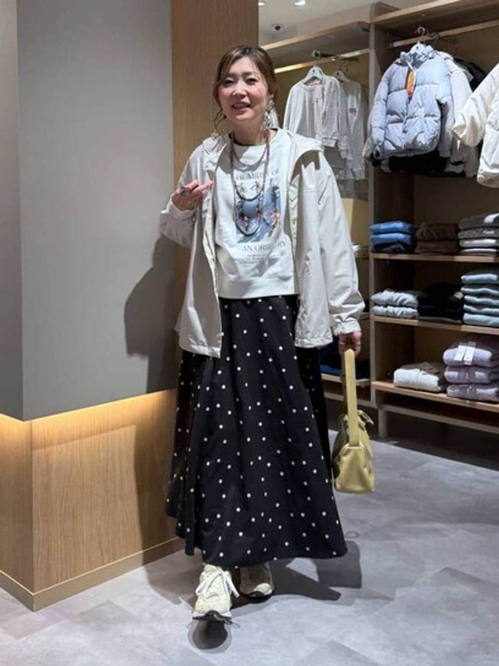 グレー系のニット/セーター、ホワイト系のスウェット、ベージュ系のマウンテンパーカーを着用したレディースの春コーディネートの2枚目の写真