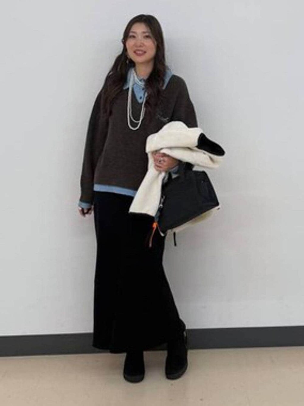 ホワイト系のブルゾン、ブラック系のボストンバッグ、ブラック系のスカートを着用したレディースの冬コーディネートの2枚目の写真