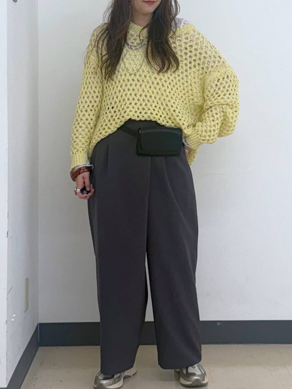 イエロー系のニット/セーター、ホワイト系のTシャツ/カットソー、ブラック系のボディバッグ/ウエストポーチを着用したレディースの秋コーディネートの5枚目の写真
