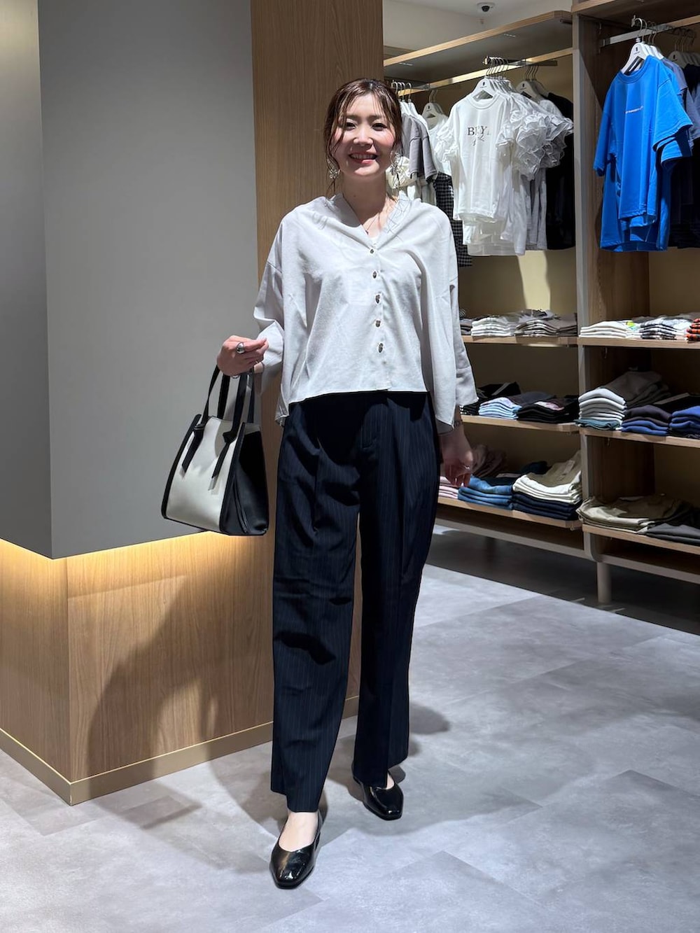 ブラック系のパンプス、ホワイト系のショルダーバッグ、ブルー系のその他パンツを着用したレディースの夏コーディネートの2枚目の写真