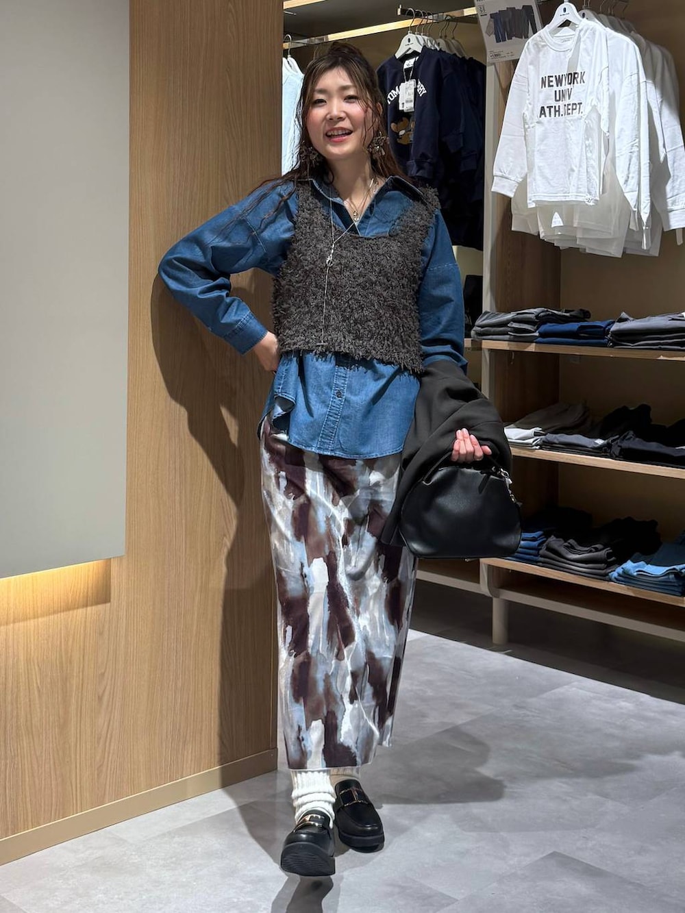 ブラック系のショルダーバッグ、ブラック系のローファー、ブルー系のシャツ/ブラウスを着用したレディースの春コーディネートの6枚目の写真