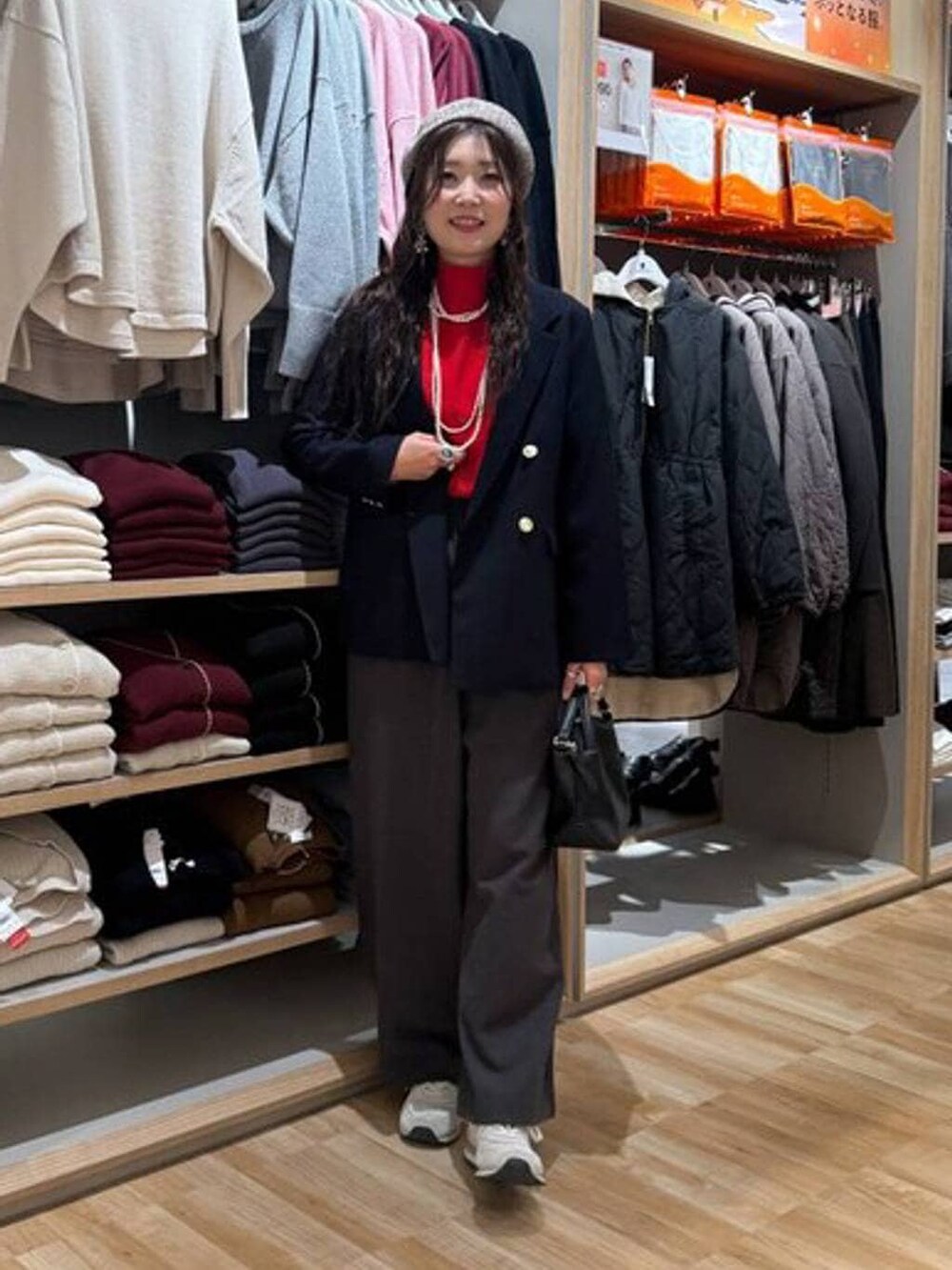 ブラック系のショルダーバッグ、レッド系のニット/セーター、ブルー系のテーラードジャケットを着用したレディースの冬コーディネートの2枚目の写真