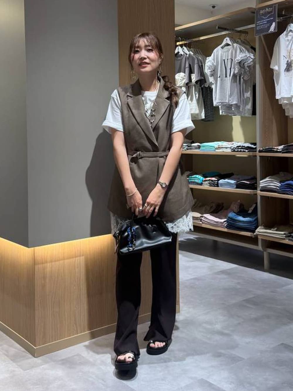 ブラウン系のベスト、ホワイト系のTシャツ/カットソー、ブラック系のボストンバッグを着用したレディースの夏コーディネートの2枚目の写真