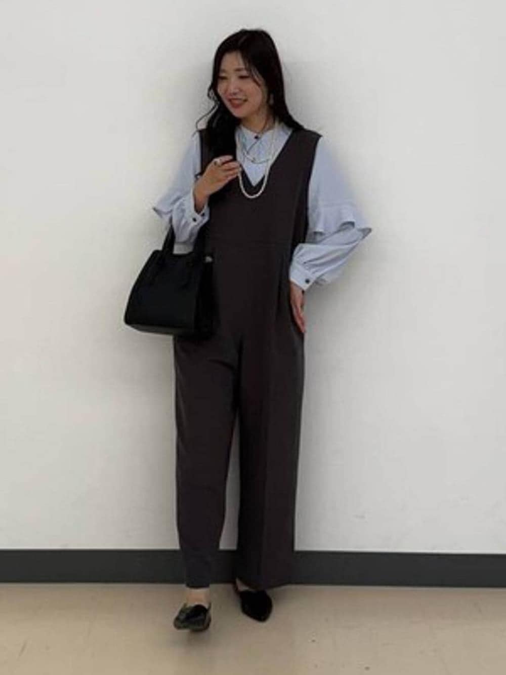 ブラック系のショルダーバッグ、ブラック系のパンプス、グレー系のセットアップを着用したレディースの冬コーディネートの2枚目の写真