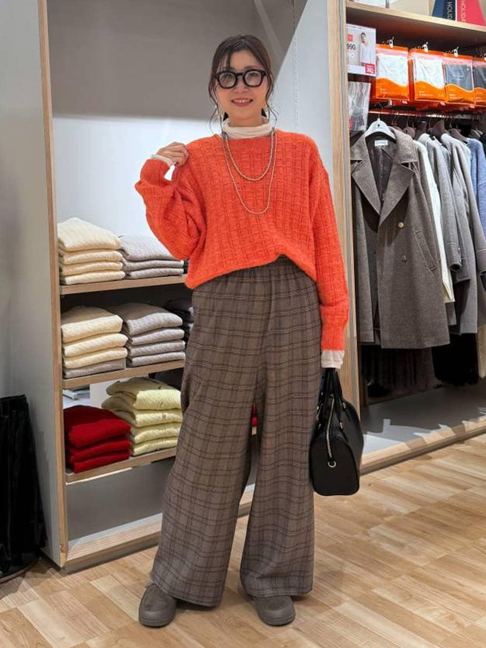 ベージュ系のダウンジャケット/コート、ホワイト系のTシャツ/カットソー、オレンジ系のニット/セーターを着用したレディースの春コーディネートの3枚目の写真