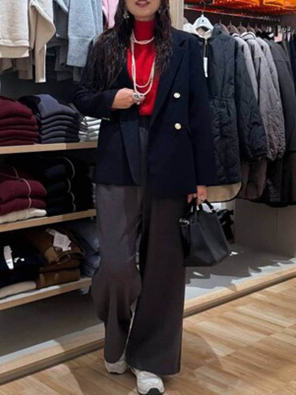 ブラック系のショルダーバッグ、レッド系のニット/セーター、ブルー系のテーラードジャケットを着用したレディースの冬コーディネートの5枚目の写真