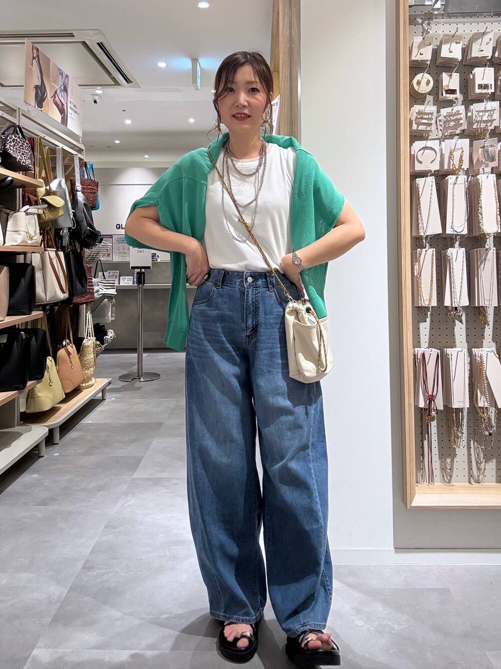 ブルー系のデニムパンツ、グリーン系のカーディガン/ボレロ、ベージュ系のボディバッグ/ウエストポーチを着用したレディースの夏コーディネートの2枚目の写真