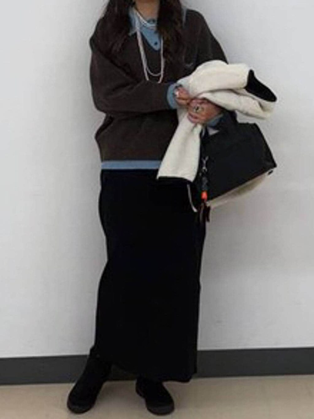 ホワイト系のブルゾン、ブラック系のボストンバッグ、ブラック系のスカートを着用したレディースの冬コーディネートの5枚目の写真