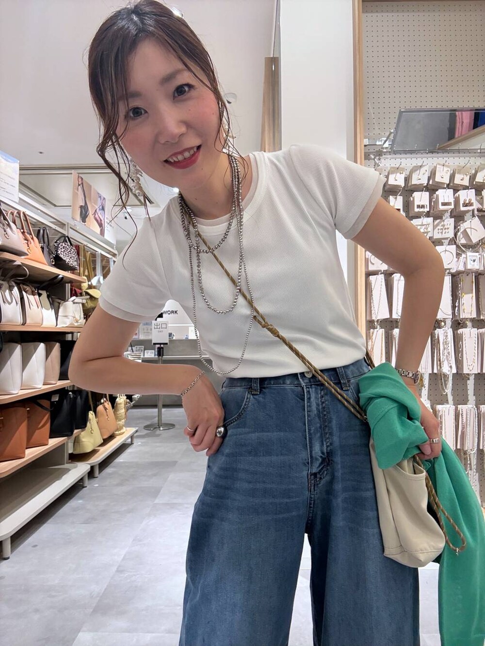 ブルー系のデニムパンツ、グリーン系のカーディガン/ボレロ、ベージュ系のボディバッグ/ウエストポーチを着用したレディースの夏コーディネートの3枚目の写真