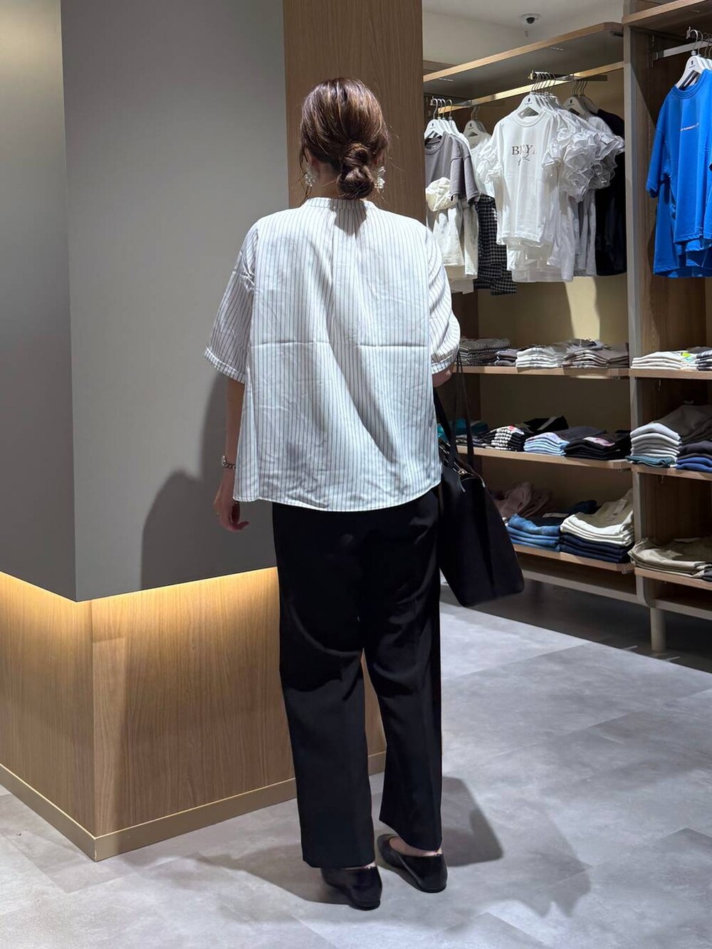 ブラック系のパンプス、ブラック系のトートバッグ、ホワイト系のシャツ/ブラウスを着用したレディースの夏コーディネートの4枚目の写真