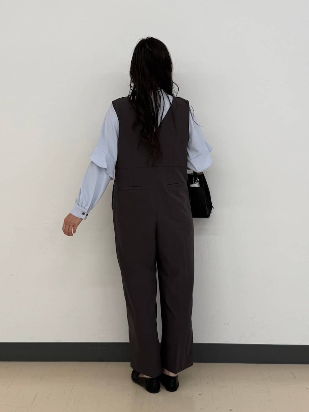 ブラック系のショルダーバッグ、ブラック系のパンプス、グレー系のセットアップを着用したレディースの冬コーディネートの5枚目の写真