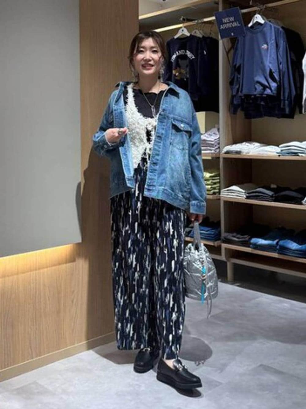 ブラック系のローファー、シルバー系のハンドバッグ、ブルー系のデニムジャケットを着用したレディースの春コーディネートの2枚目の写真